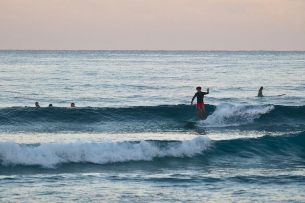 Surfers riding waves at sunset in Rincón on Puerto Rico's west coast.